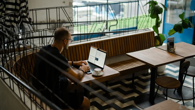 Per Starke arbeitet am Laptop an einem Tisch im Café, von schräg oben fotografiert